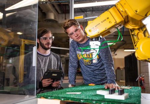 工业工程专业的学生学习如何对自动化设备进行编程，以帮助在制造领域工作的人类.